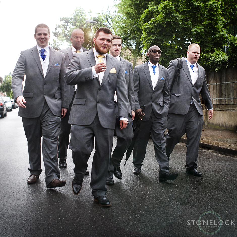 A groom his best man & ushers walk to the wedding ceremony in the style of reservior dogs