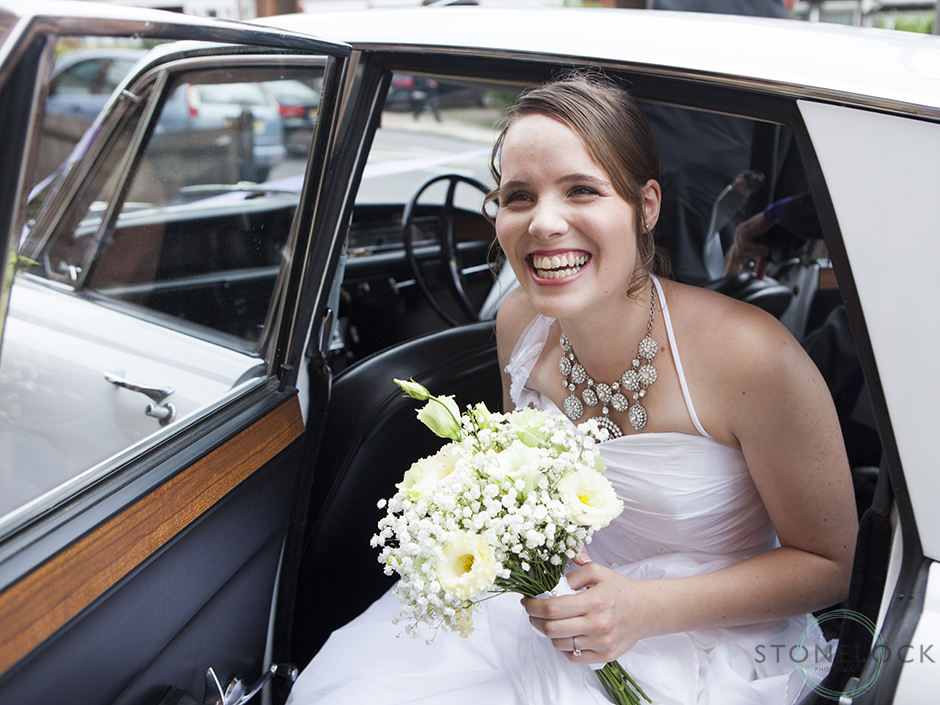 A bride arrives in the wedding car at the wedding ceremony with a big smile on her face, at Mitcham Lane Baptist Church