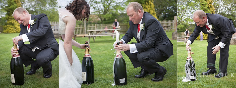 The groom opens a large bottle of champagne at the wedding reception