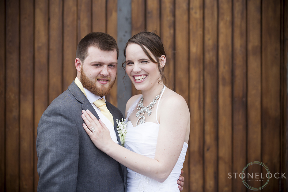 The bride and groom pose in front of a wooden door