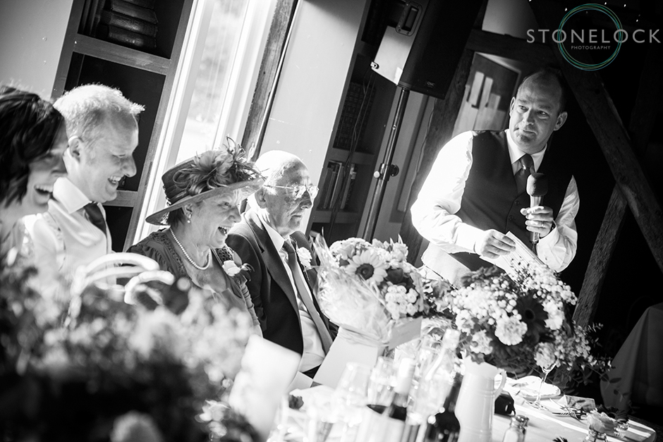 The mother of the groom laughs during the wedding speeches shot in black & white