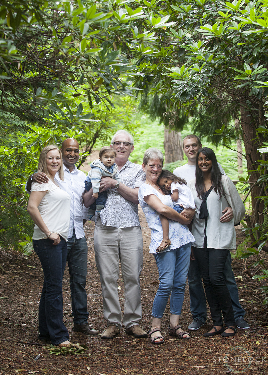 A family photo shoot in Coombe Wood, Croydon with grandparents, adult children and grandchildren. The family stand in the wood, amongst the trees