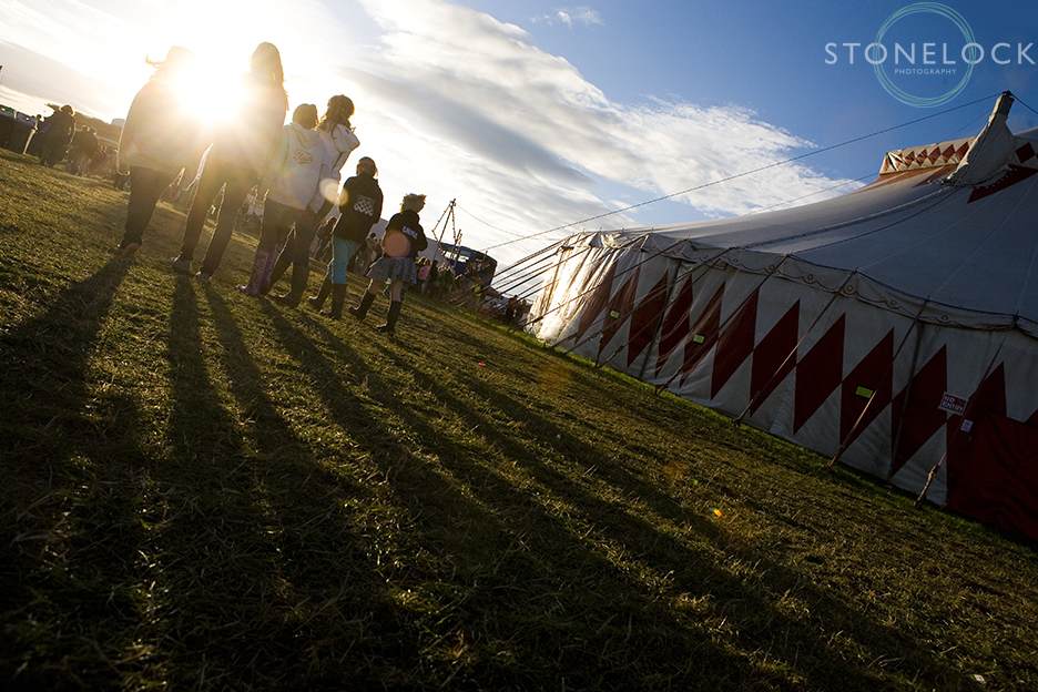 A group of people walk into the setting sun outside the big top tent at Greenbelt Arts Festival held at Cheltenham Racecourse