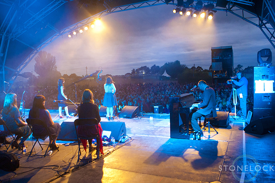 A photograph shot from the back of MainStage at Greenbelt Arts Festival looking our over the crowds listening to The Unthanks perform at dusk