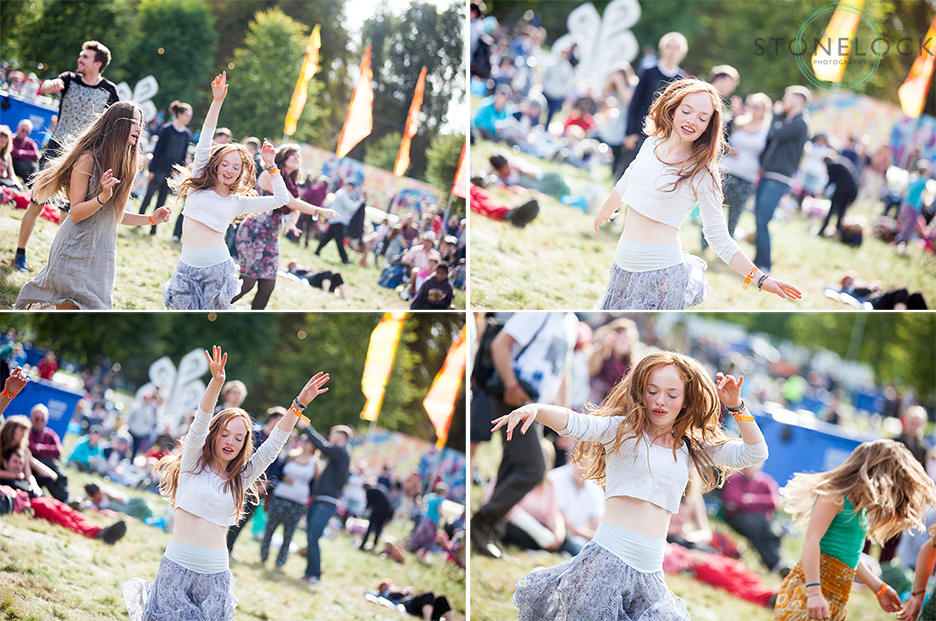 A girl dances at on the grass by MainStage at Greenbelt Arts Festival with the sun behind her, she is into the music and having a good time