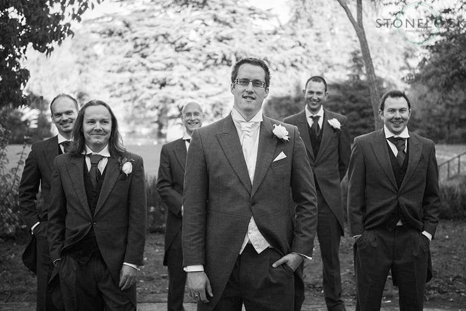 The groom and his ushers stand looking at the camera, they are relaxed with hands in pockets for a contemporary wedding photo