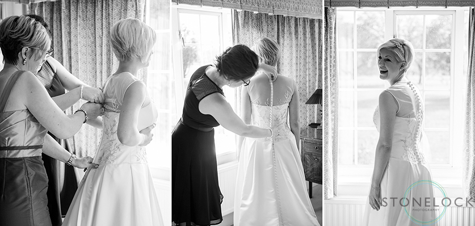 The brides Mum and sister help her put on her dress before her wedding
