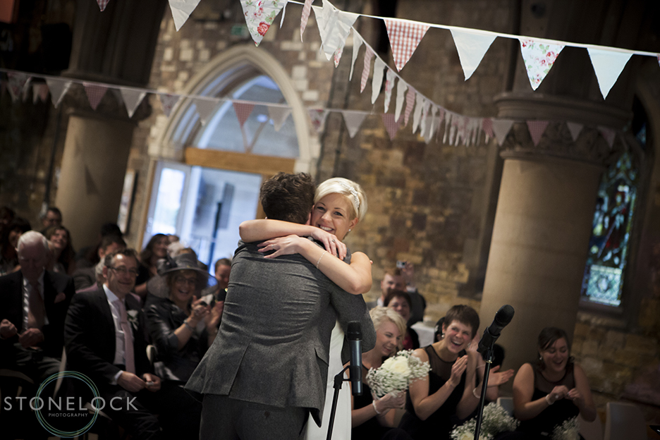 A photo of the bride and groom embracing during their wedding ceremony at Woodlands Church in Bristol