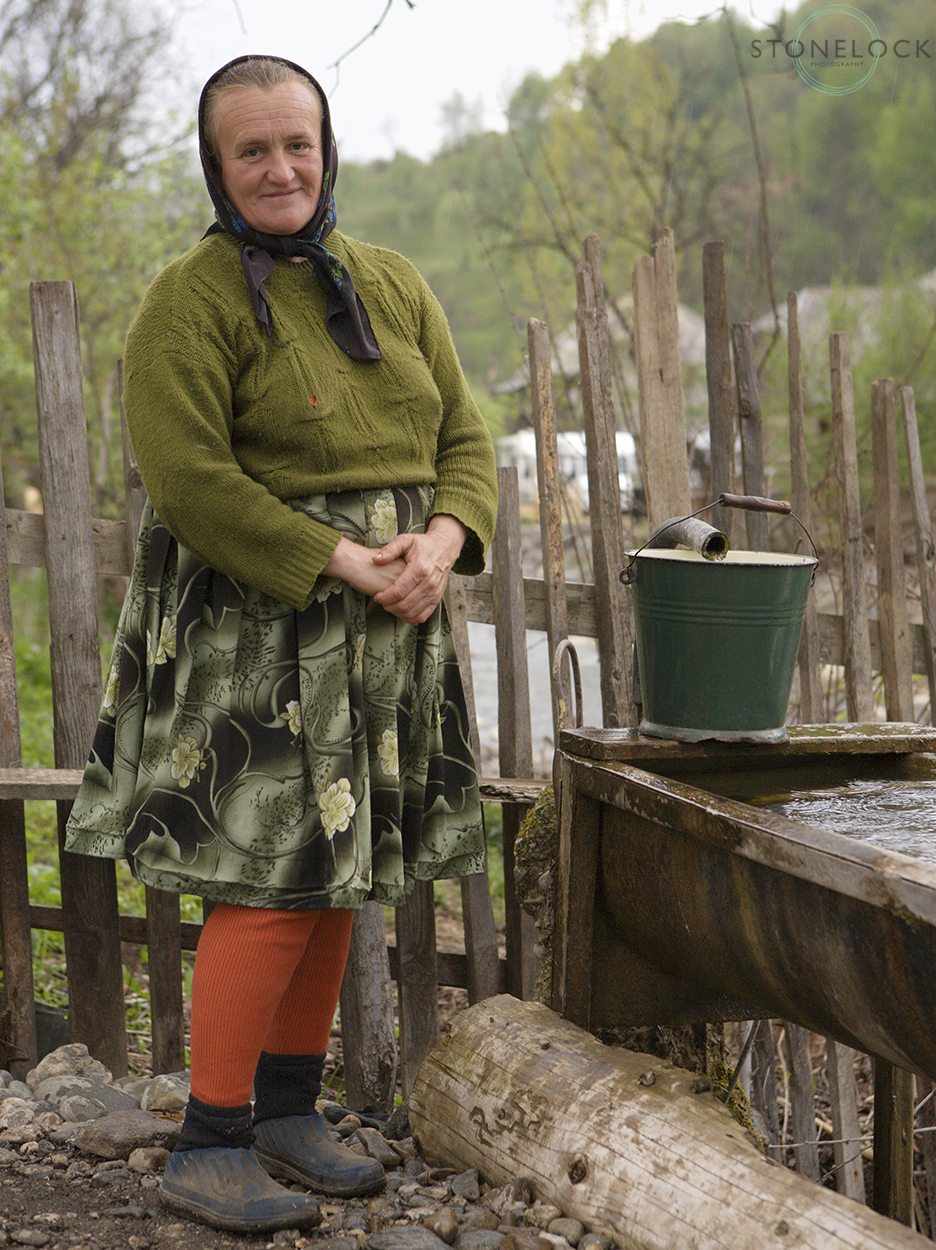 A woman collecting water from the village tap, Botiza Village, Maramures, Romania,