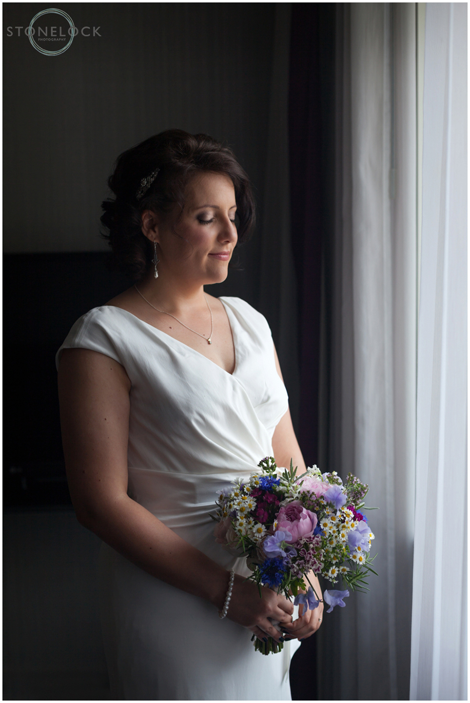 A gorgeous photo of a bride standing in from of a window