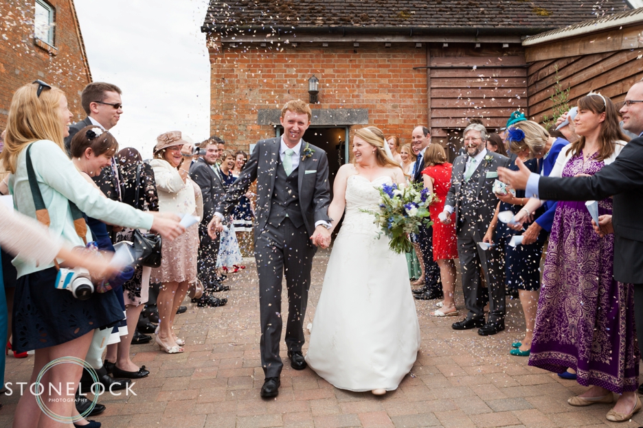 The bride and groom with confetti at Bassmead Manor Barns in Cambridgeshire