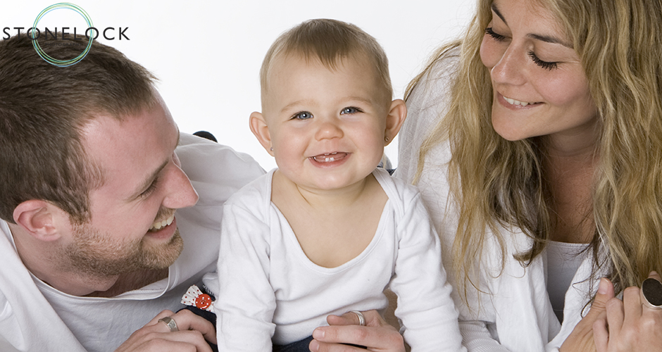 A young family of three with a baby posing in a photography studio on a white background