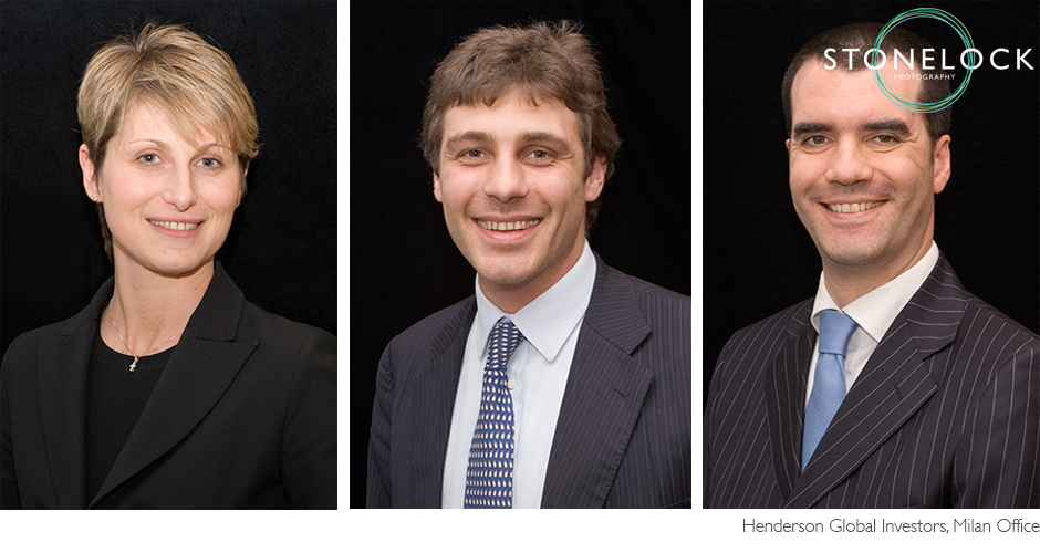 Three people pose for a corporate portrait against a dark black background